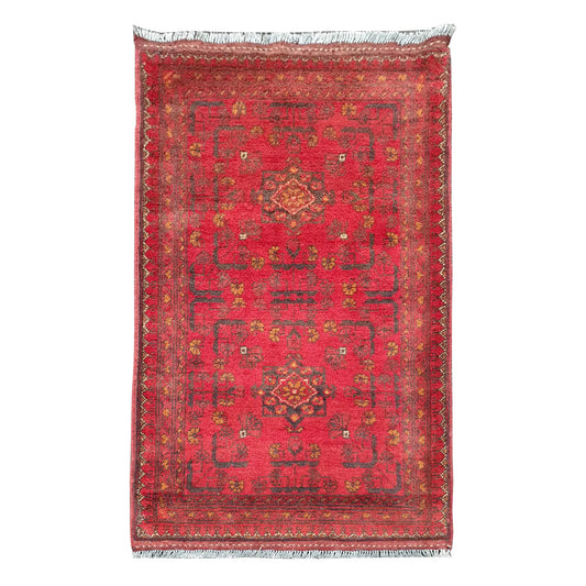 Full view of Afghan Khal Mohammadi hand-knotted wool rug with warm red field, central geometric medallion and patterned border, 106 x 56 cm