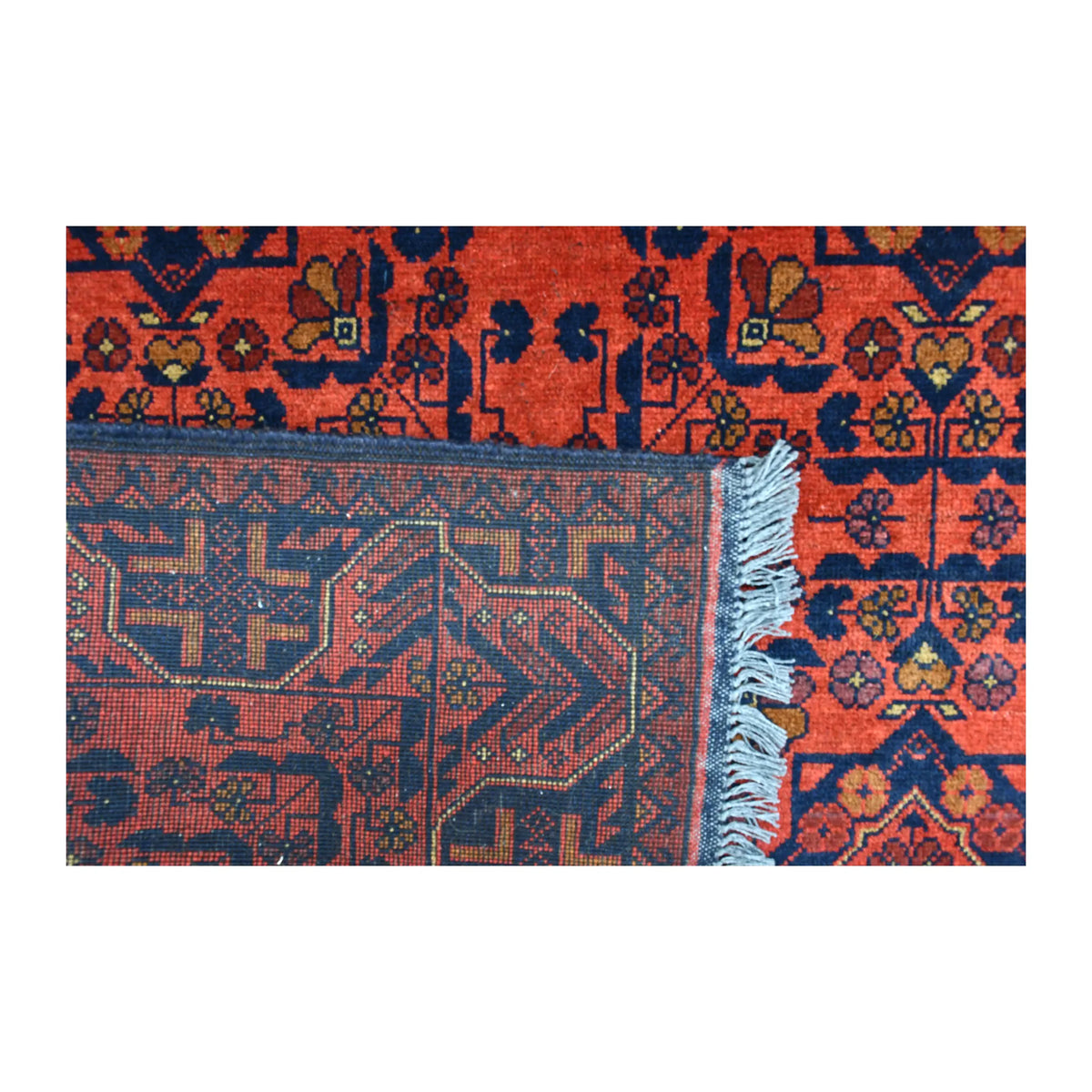 Folded-corner detail of Khal Mohammadi rug showing the reverse weave, rich red patterned front and pale fringe