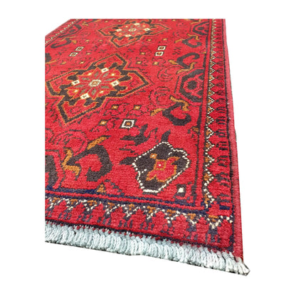 Angled corner and fringe view of Afghan Khal Mohammadi wool rug showing deep red field, dark border detail and light fringe