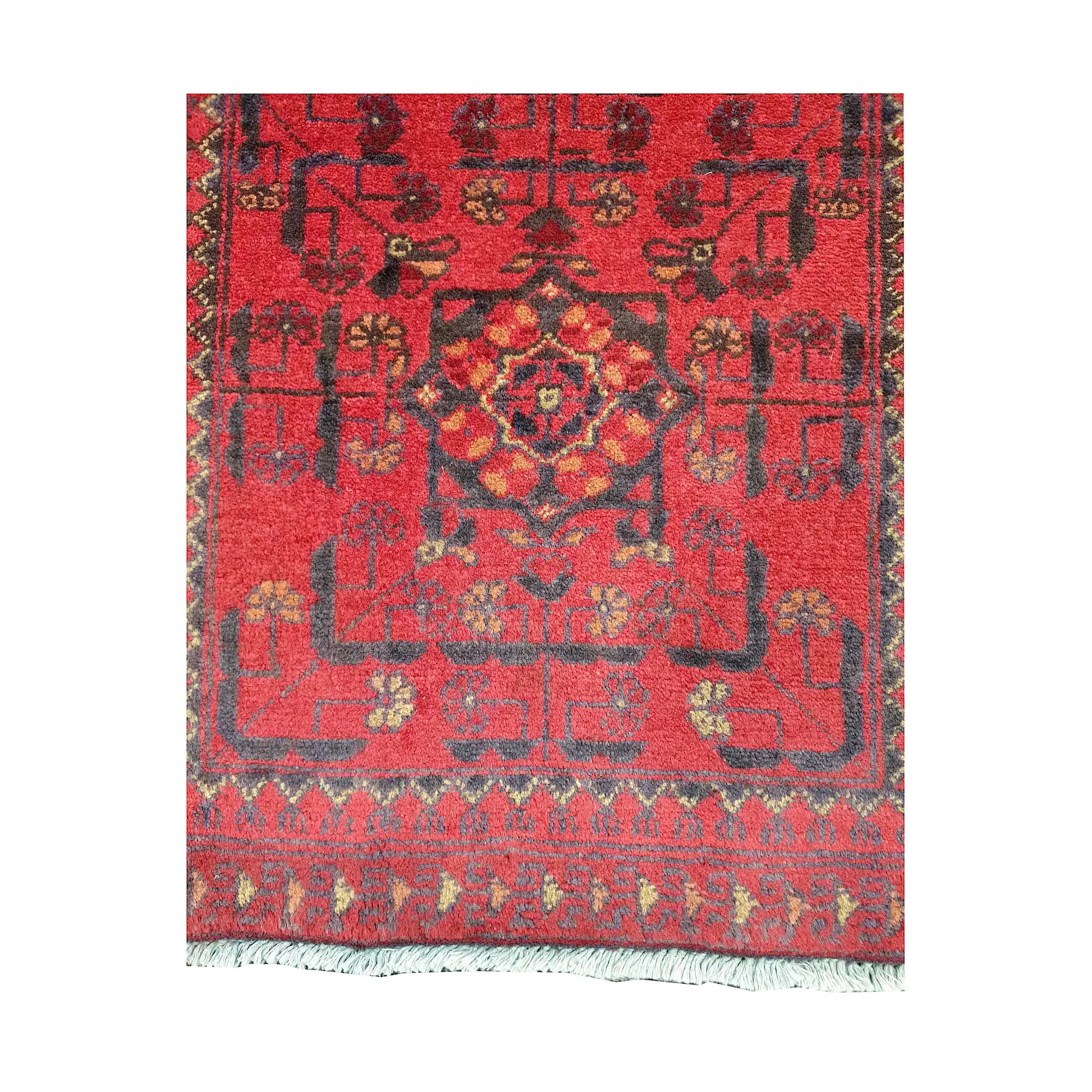 Field and border detail of Afghan Khal Mohammadi hand-knotted rug showing red ground, dark geometric motifs and patterned border