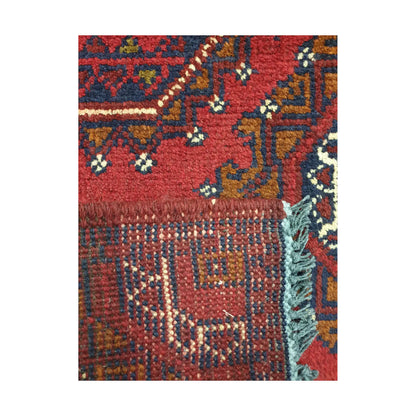 Folded corner detail of Afghan Khal Mohammadi wool rug showing the back, fringe and red front pattern