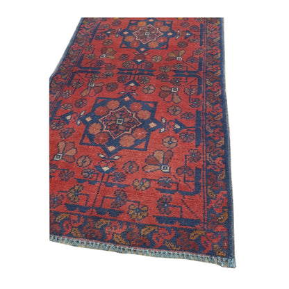 Angled detail of Afghan Khal Mohammadi rug showing the red patterned field, layered border and visible fringe edge