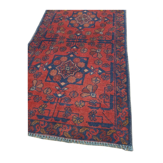 Angled detail of Afghan Khal Mohammadi rug showing the red patterned field, layered border and visible fringe edge