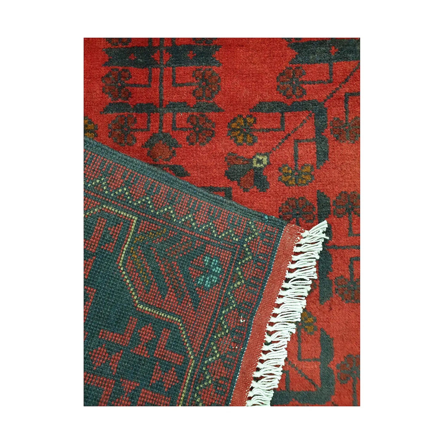 Folded corner detail of Afghan Khal Mohammadi rug showing the back of the rug, fringe and red front pattern