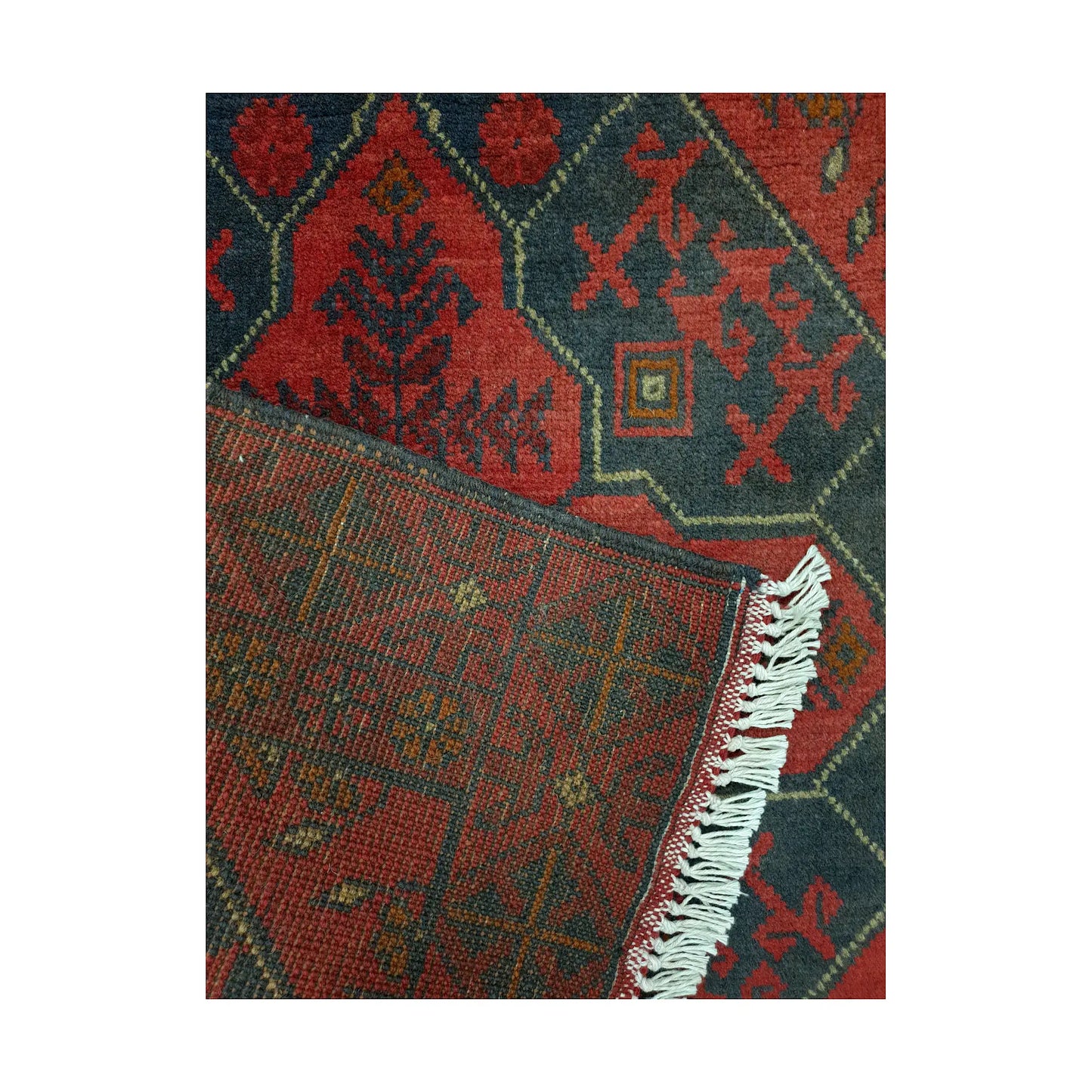 Folded corner detail of Afghan Khal Mohammadi rug showing the back of the rug, fringe and red front pattern