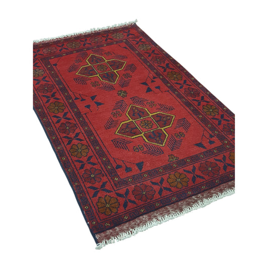 Angled full view of Afghan Khal Mohammadi wool rug showing the deep red field, paired geometric medallions and patterned border
