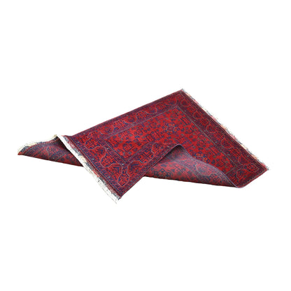 Folded view of Afghan Khal Mohammadi rug showing its red and navy floral pattern, geometric borders and exposed reverse weave