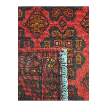 Folded corner detail of Afghan Khal Mohammadi wool rug showing the back, fringe and red front pattern