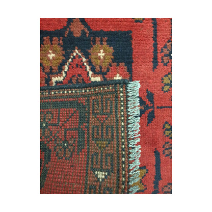 Folded corner detail of Afghan Khal Mohammadi wool rug showing the back, fringe and red front pattern