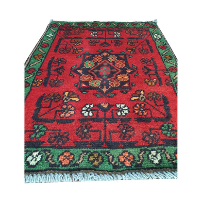Afghan Khal Mohammadi wool rug detail showing red field, central floral medallion and scattered tribal motifs