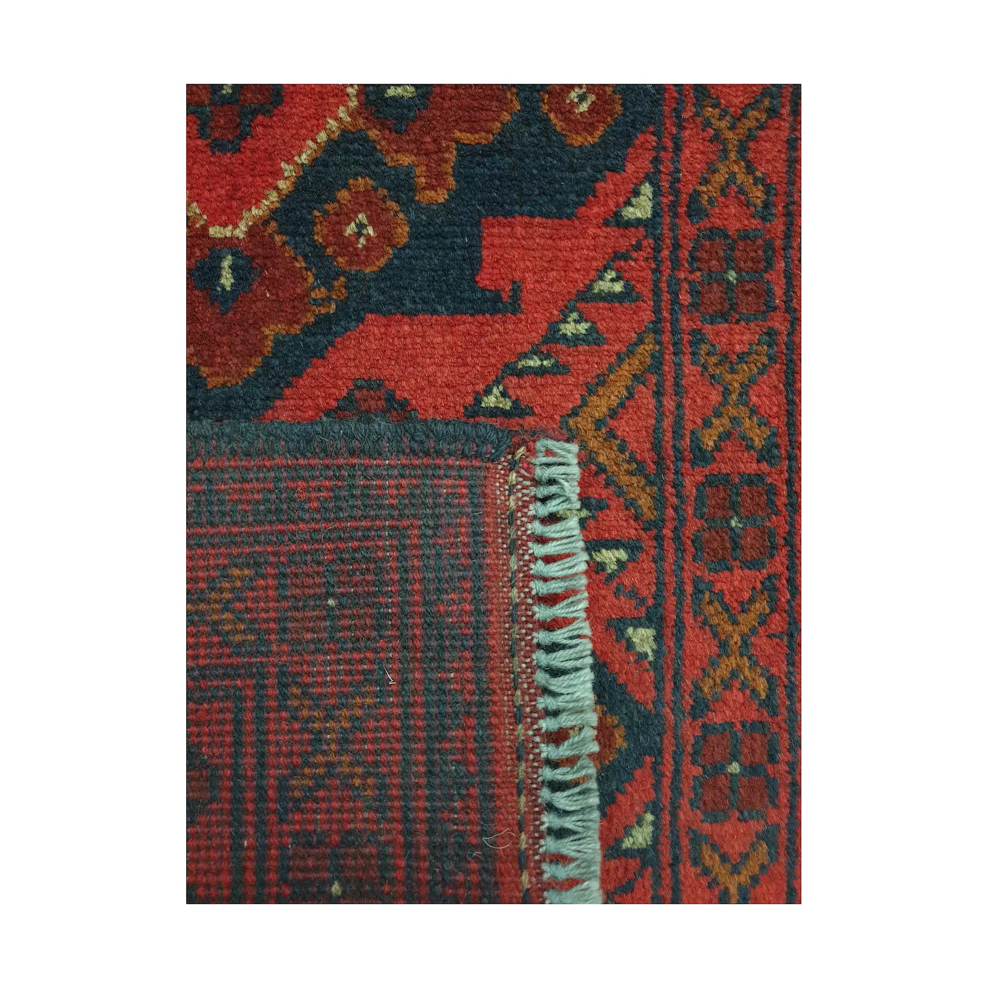 Folded corner detail of Afghan Khal Mohammadi wool rug showing the back, fringe and red geometric surface