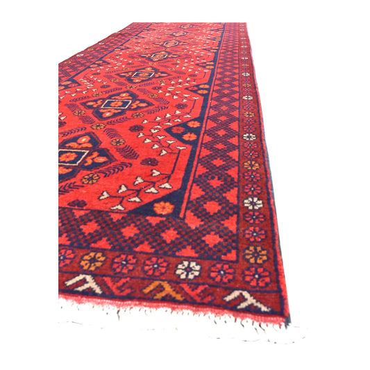 Angled view of Afghan Khal Mohammadi runner showing its deep red medallion field, layered geometric borders and white fringe