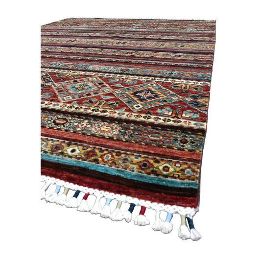 Angled view of Afghan Khurjeen wool rug showing its striped field, diamond medallion band and pale fringe