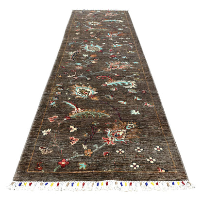 Full view of Afghan Khurjeen hand-knotted wool runner with colourful botanical motifs on a deep brown field, 299 x 80 cm