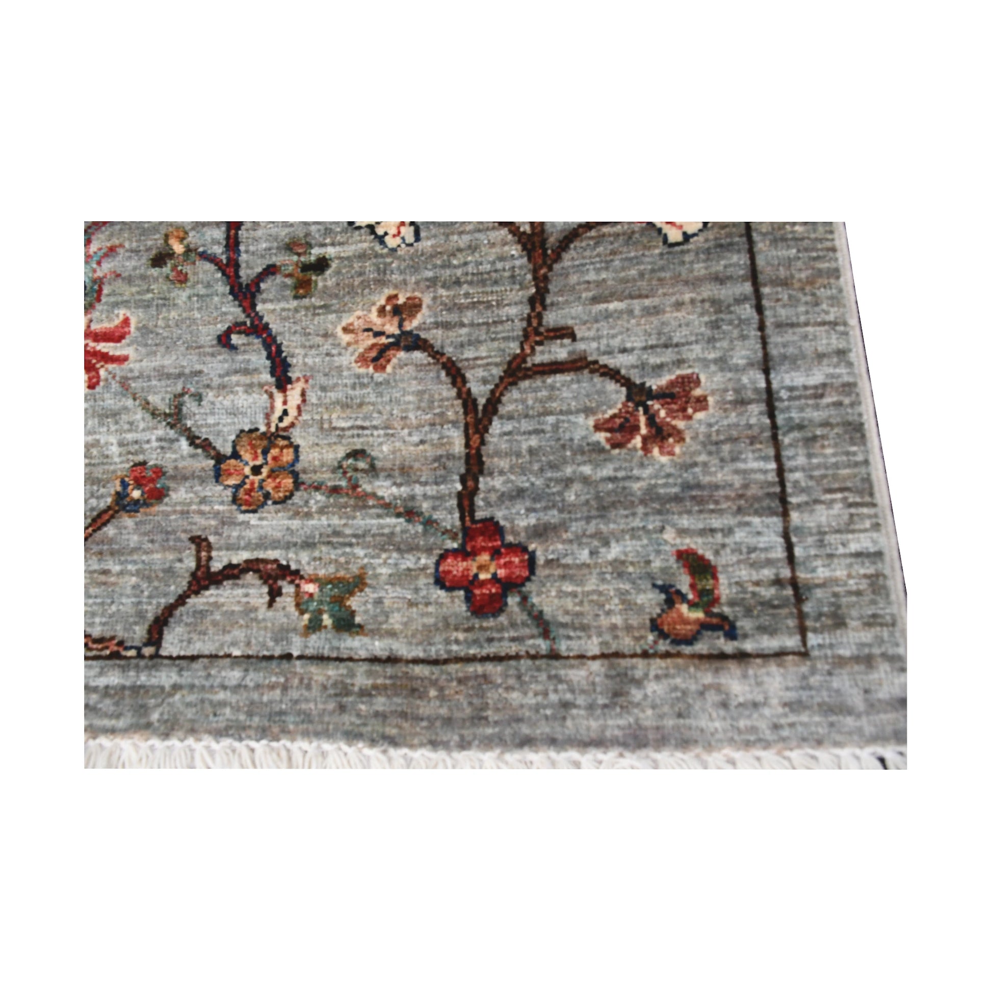 Fringe end detail of Afghan Khurjeen runner rug showing grey field, floral vine pattern and wool texture