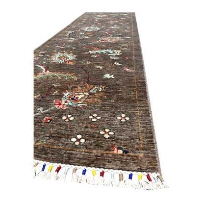 Angled end view of Afghan Khurjeen runner showing its brown field, botanical motifs and multicoloured fringe