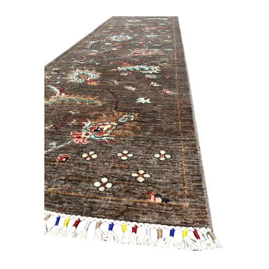 Angled end view of Afghan Khurjeen runner showing its brown field, botanical motifs and multicoloured fringe