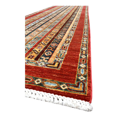 Angled corner of Afghan Khurjeen runner showing the rust-red frame, patterned bands and ivory fringe