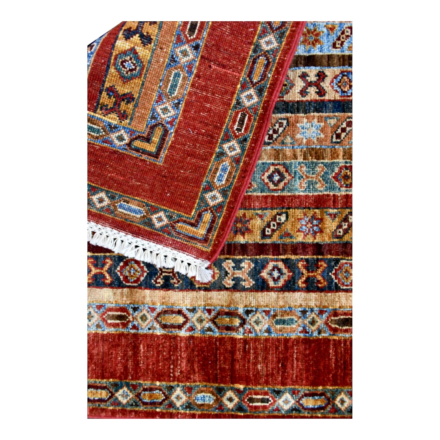 Folded fringe end of Afghan Khurjeen runner showing the rust-red border and patterned face beneath