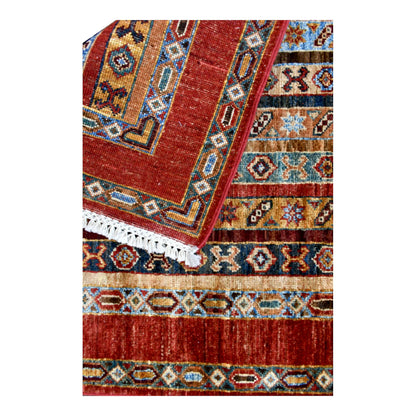 Folded fringe end of Afghan Khurjeen runner showing the rust-red border and patterned face beneath