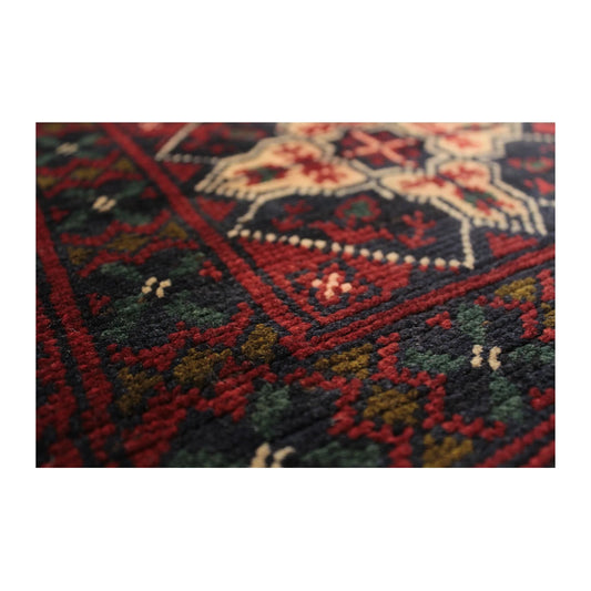 Close-up of Afghan Kunduz rug showing a maroon floral gul motif and wool pile texture