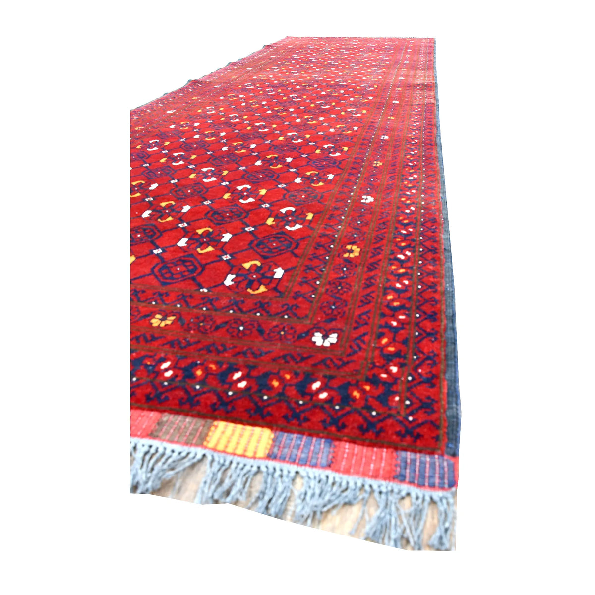 Angled view of Afghan Kunduz runner showing its dense red geometric field, narrow patterned borders and blue-grey fringe