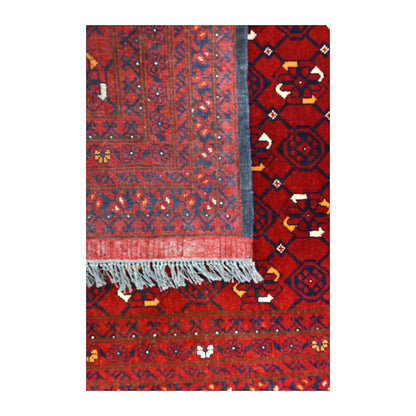 Folded-corner detail of Afghan Kunduz runner showing the reverse weave beside its dense red geometric front and blue-grey fringe