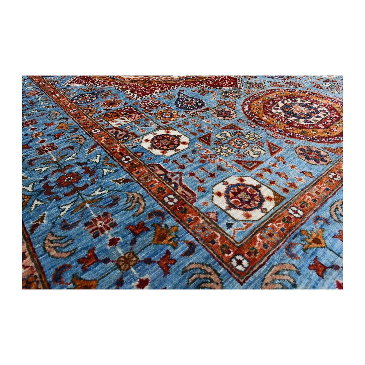 Angled corner and border detail of Afghan Mamluk wool rug showing blue field, floral motifs and layered rust border