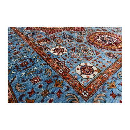 Angled corner and border detail of Afghan Mamluk wool rug showing blue field, floral motifs and layered rust border