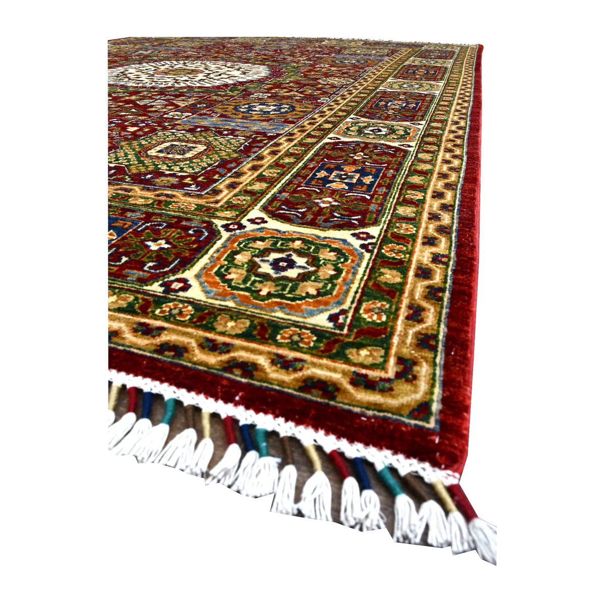 Angled view along the Afghan Mamluk rug showing its red field, gold-toned border and white fringe.
