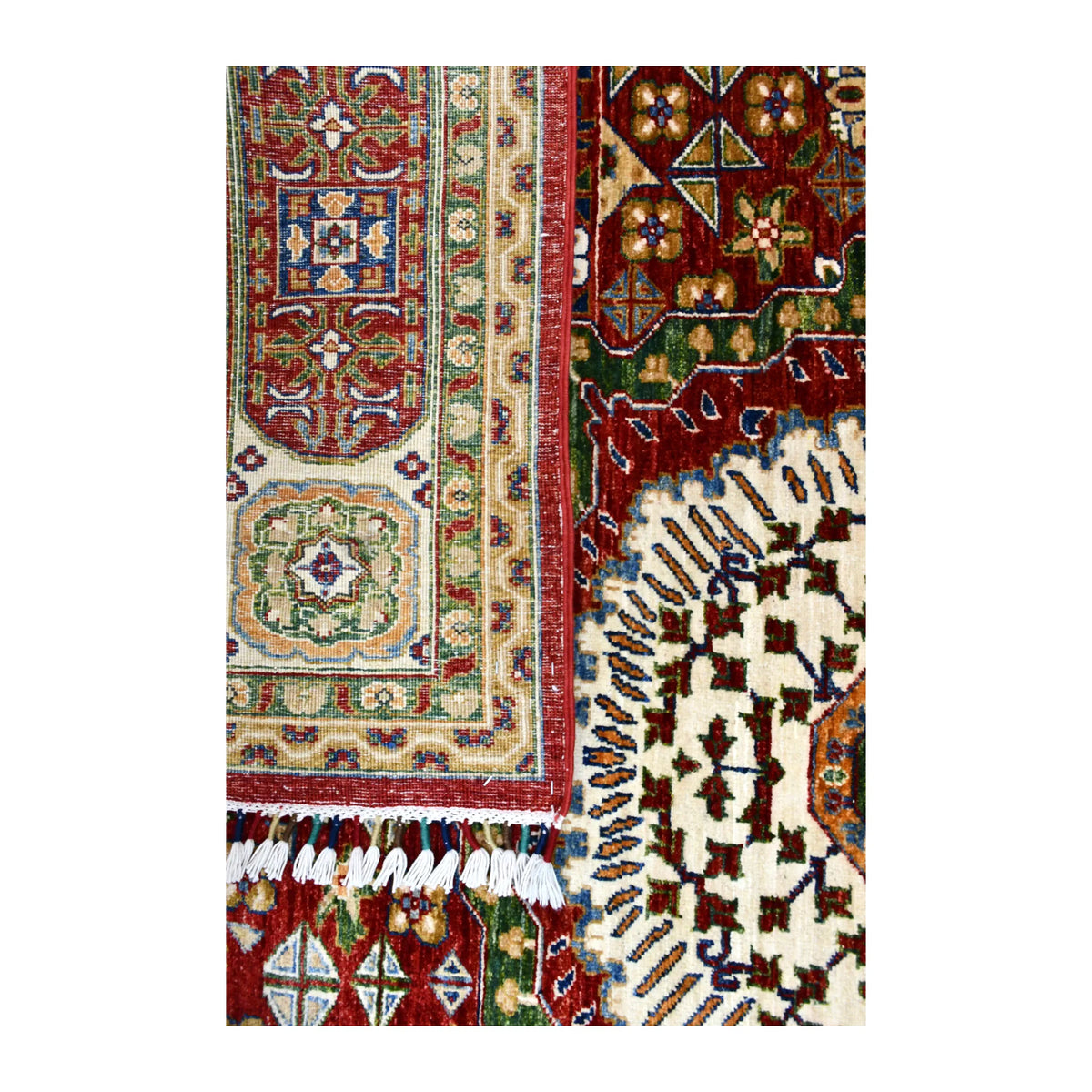 Close-up of the folded rug showing the patterned reverse beside the cream medallion and white fringe.