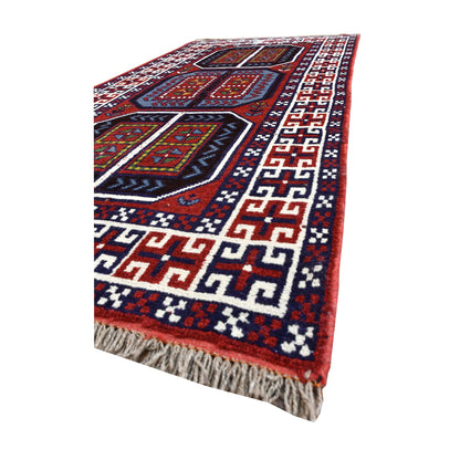 Angled view of Afghan Mashwani rug showing its deep red field, three geometric medallions, ivory border and pale fringe
