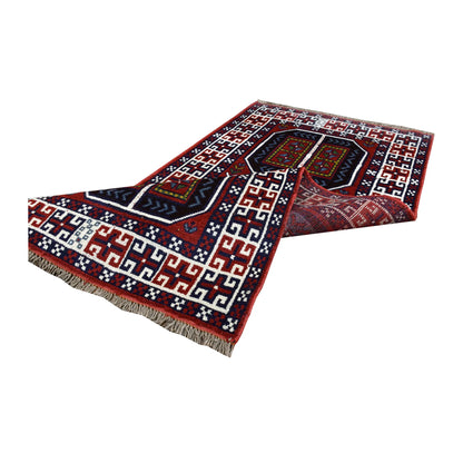 Folded view of Afghan Mashwani rug showing its patterned wool pile, geometric field, ivory border and fringe