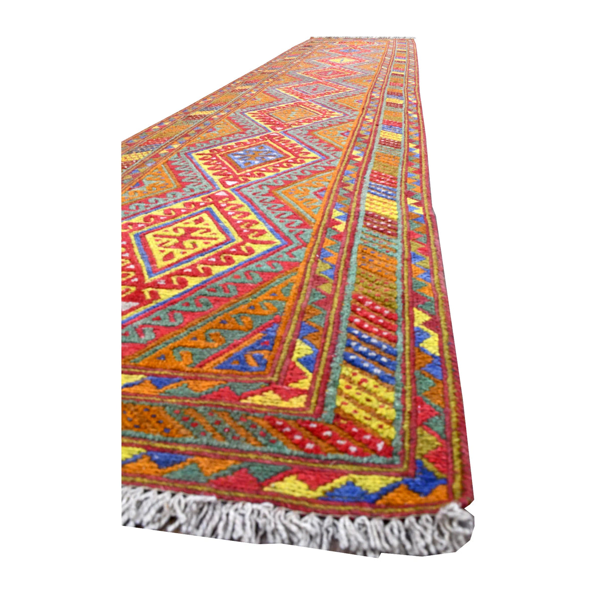 Angled view of Afghan Mashwani runner showing its rust-orange field, stepped diamond motifs, layered borders and light-grey fringe