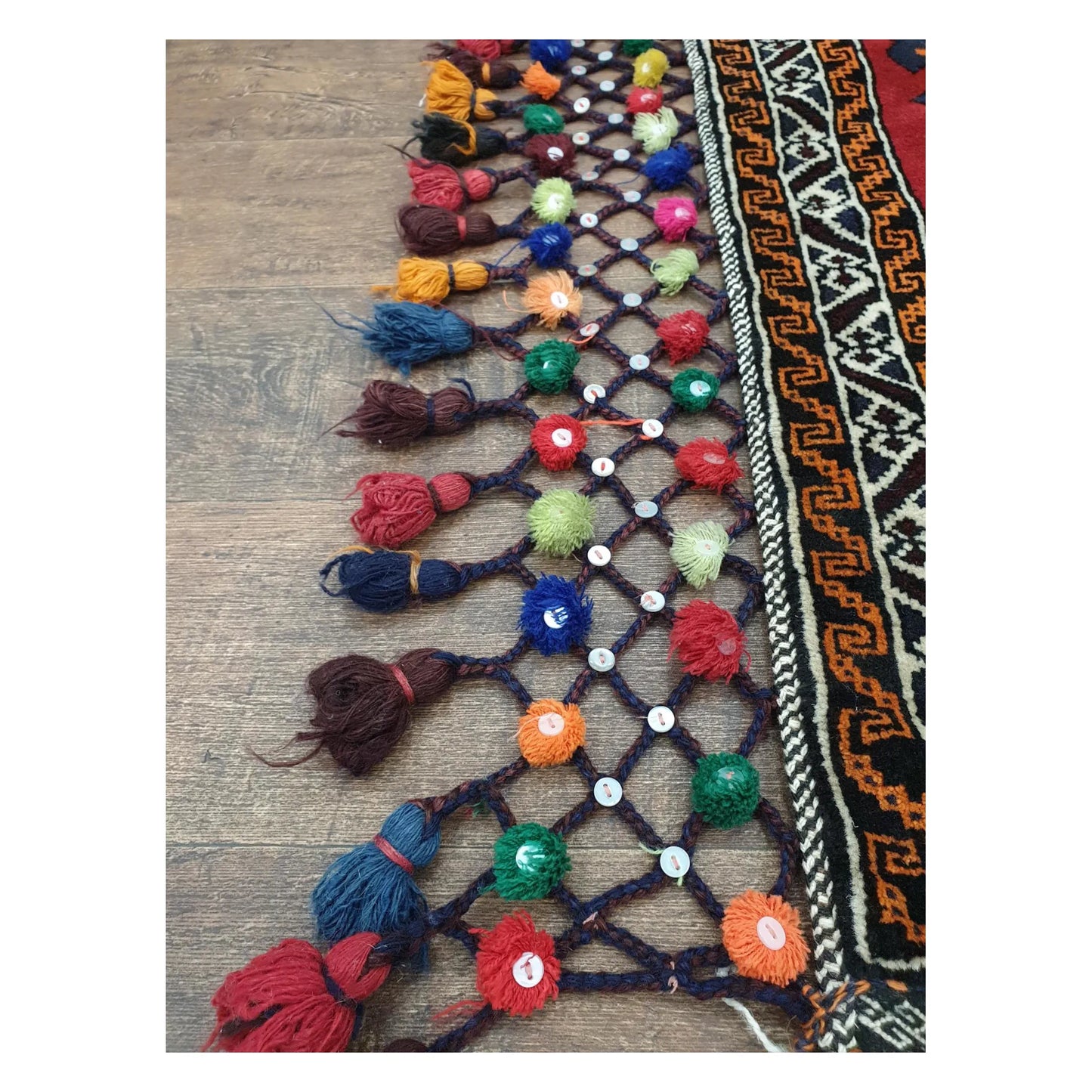 Close-up of Afghan Pushti wool pillow cover showing colourful side tassel detail