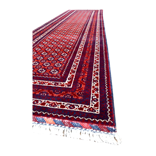 Angled view of Afghan Roshnai runner showing its repeating motif field, multiple patterned borders and white fringe