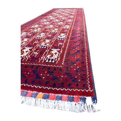 Angled view of Afghan Roshnai wool runner showing ivory motifs, navy and plum borders, striped end finish and white fringe