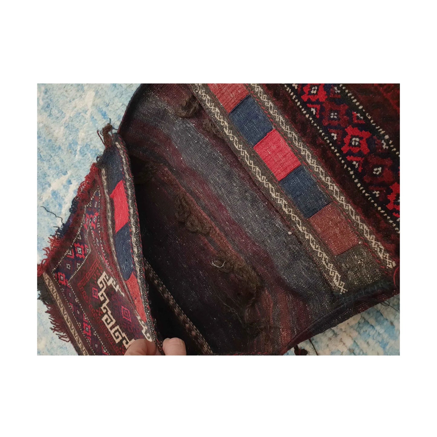 Open compartment view showing dark flatweave and red, navy and ivory woven bands on the Afghan saddle bag