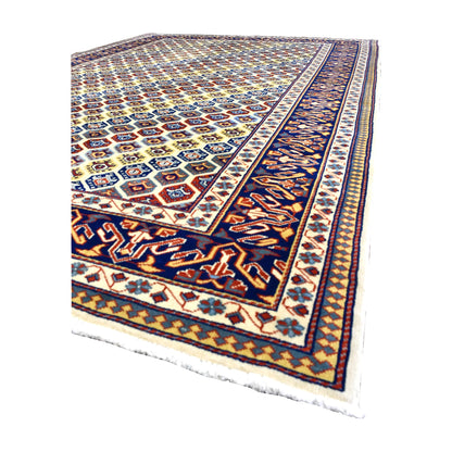 Angled view of Afghan Shirvan wool rug showing its intricate geometric field, deep navy border, wool pile and pale fringe