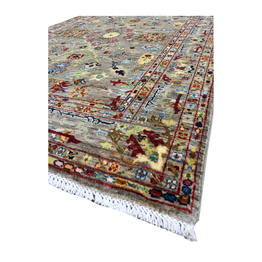 Angled view of Afghan Sultani rug showing pale blue, red, olive and gold motifs, layered borders and pale fringe