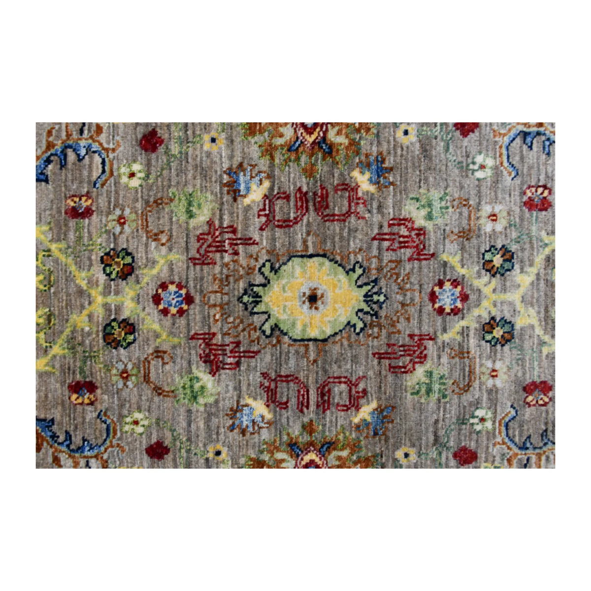 Central medallion detail of Sultani rug with yellow-gold floral centre, red geometry and small blue and green motifs