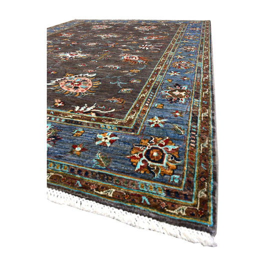 Angled view of Afghan Sultani wool rug showing its dark brown field, colourful palmettes, broad blue border and white fringe