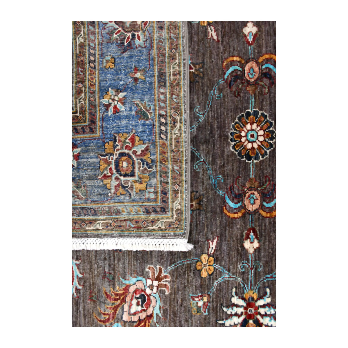 Folded-corner detail of Afghan Sultani rug showing the reverse weave, blue floral border, dark brown front and white fringe