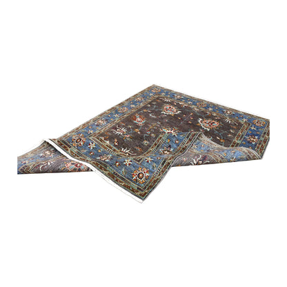 Folded view of Afghan Sultani hand-knotted wool rug showing its open floral field, broad blue border and white fringe