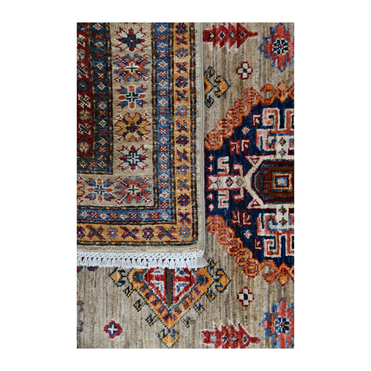 Folded-corner detail of Super Kazak rug showing the reverse weave, patterned pile and pale fringe