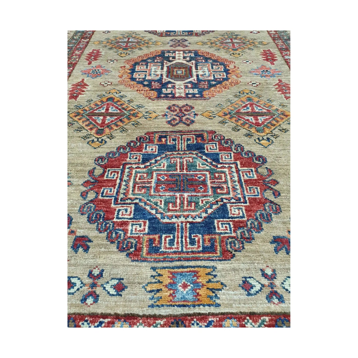Afghan Super Kazak hand-knotted wool rug styled with chair showing beige, red and blue geometric design