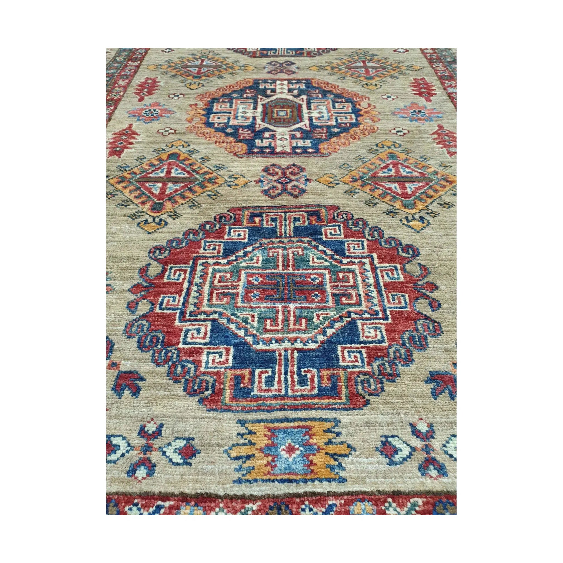 Afghan Super Kazak hand-knotted wool rug styled with chair showing beige, red and blue geometric design