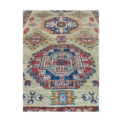 Afghan Super Kazak hand-knotted wool rug styled with chair showing beige, red and blue geometric design