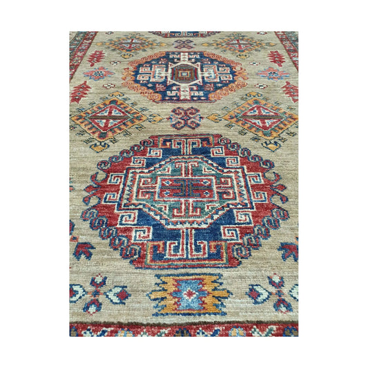 Afghan Super Kazak hand-knotted wool rug styled with chair showing beige, red and blue geometric design