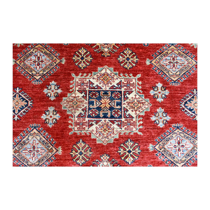 Close-up of the central square medallion in blue, ivory and tan, surrounded by diamond motifs on the red field